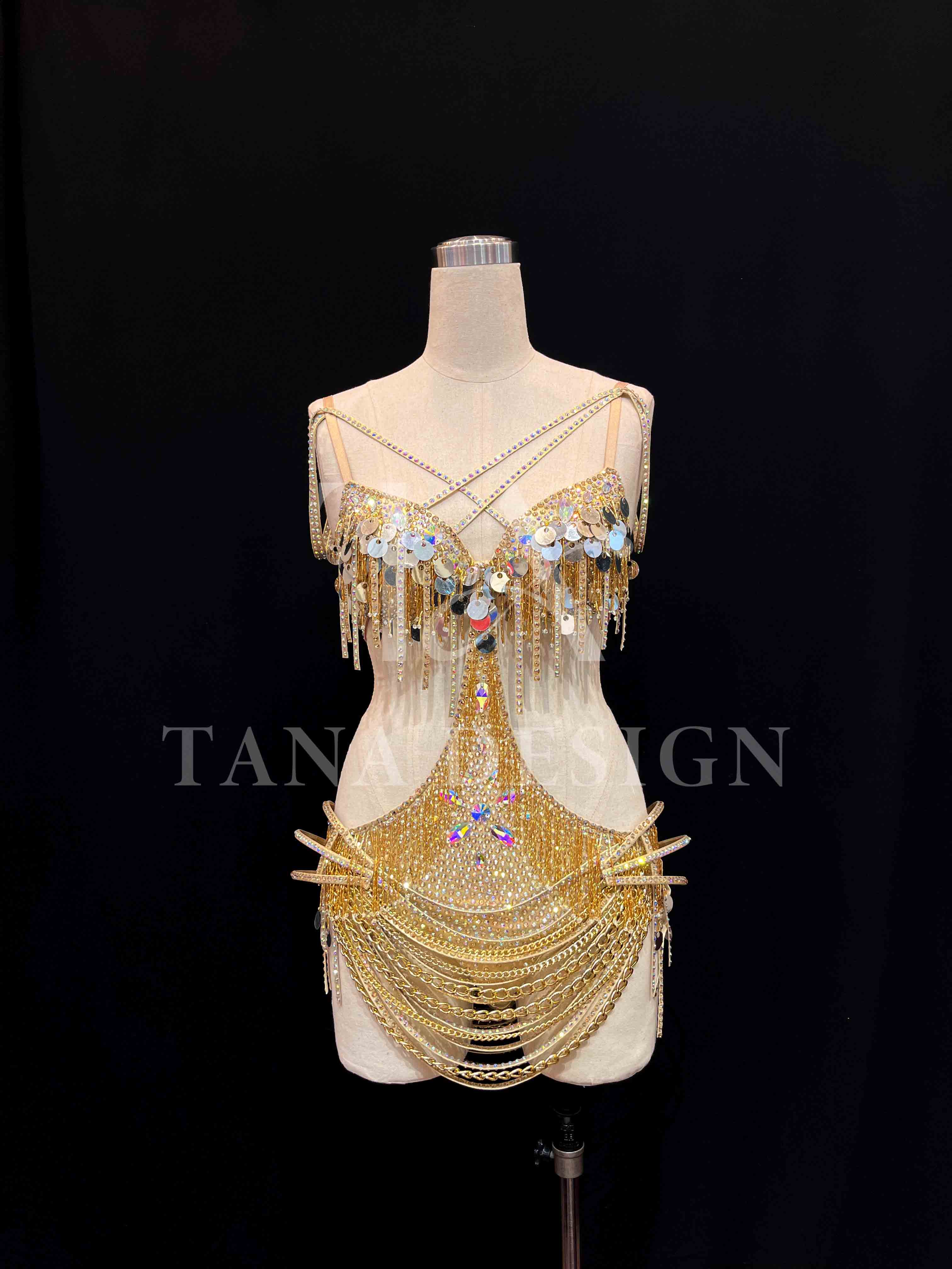 tana-women-competition-latin-dance-dress-gold-holographic (1) Gold holographic women competition Latin dance dress with open back, gold chains, and rhinestone fringe by Tana Dancewear.
