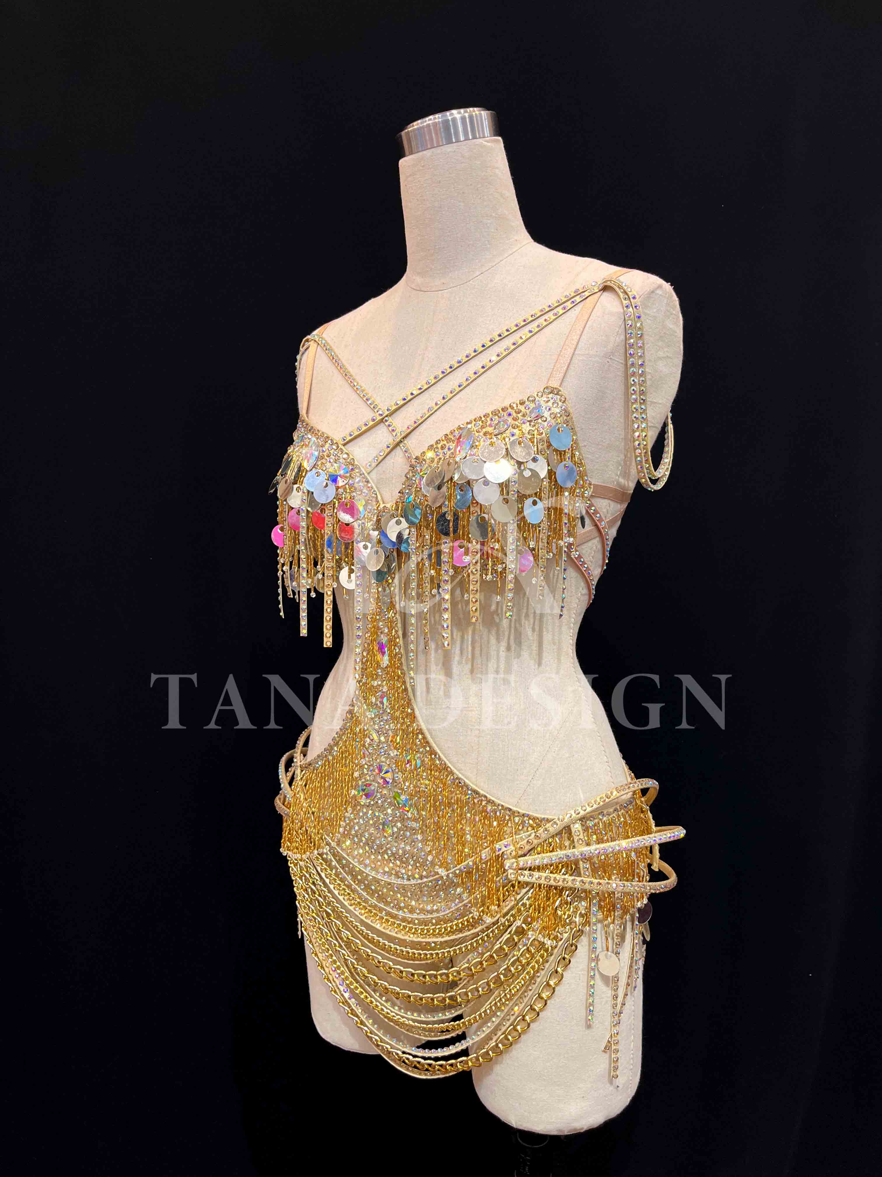 tana-women-competition-latin-dance-dress-gold-holographic (3) Gold holographic women competition Latin dance dress with open back, gold chains, and rhinestone fringe by Tana Dancewear.